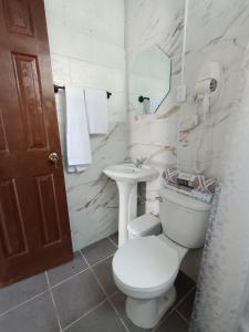 a white bathroom with a toilet and a sink at Luxury Hostel Teresita in San Salvador