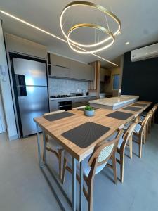 a kitchen with a wooden table with chairs and a chandelier at Apto Cancún Foz in Foz do Iguaçu