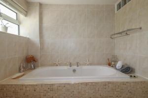 a white bath tub in a tiled bathroom at Coastman's Nest in Newquay +44 photos