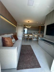 a living room with a white couch and a kitchen at Apto Cancún Foz in Foz do Iguaçu