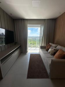 a living room with a couch and a large window at Apto Cancún Foz in Foz do Iguaçu