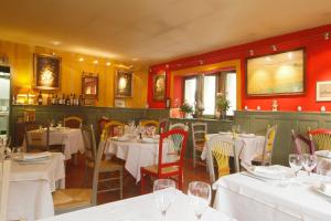 a restaurant with white tables and chairs and red walls at Hostellerie et la parenthese uzes in Uzès