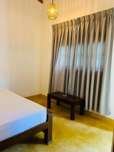 a bedroom with a bed and a table next to a window at Villa 66 Ahangama in Ahangama +5 photos