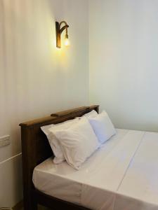 a bed with two pillows and a light on the wall at Villa 66 Ahangama in Ahangama