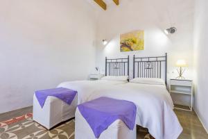 a white bedroom with a large bed with purple comforter at Fora Vila in Manacor +21 photos