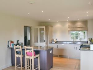 a kitchen with two bar stools and a counter at Brookside Cottage in Burley