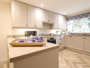 a kitchen with white cabinets and a counter top at 6 Uppergate Street Rose Cottage in Conwy