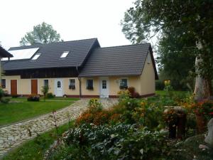 uma casa com um telhado preto e um jardim em Ferienwohnung am Storchennest em Schmogrow