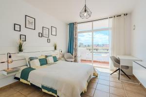 a white bedroom with a large bed and a desk at Marina Palace with Swimming Pool in Adeje