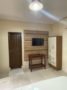 Canaã dos CarajásにあるHOTEL QUALITY PLUSのテレビ、テーブル、冷蔵庫が備わる客室です。