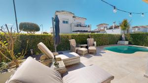 a patio with chairs and an umbrella and a pool at Casa NY - A Murcia Holiday Rentals Property in Roldán