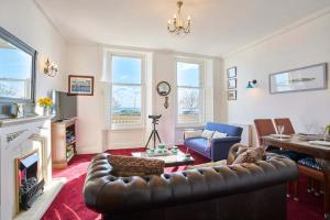 a living room with a leather couch and a fireplace at Host & Stay - The Aquamarine Weymouth Beach in Weymouth