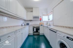 a kitchen with white cabinets and a green floor at Ericeira Panoramic Sea View Apartments in Ericeira