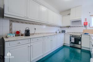 a white kitchen with blue floors and white cabinets at Ericeira Panoramic Sea View Apartments in Ericeira
