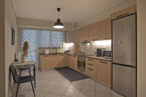 una cucina con armadi in legno, sedia e frigorifero di Denimou Home Luxurious 2BR Fully Equipped, Balcony a Pireo