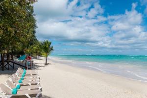 a row of white lounge chairs on a beach at Impressive Punta Cana - All Inclusive in Punta Cana