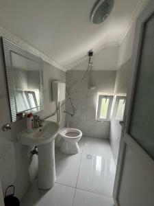 a white bathroom with a sink and a toilet at Guest House Besi in Fierzë