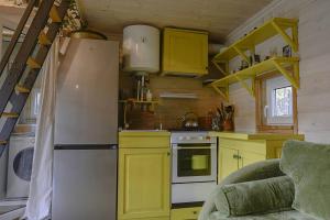 a kitchen with yellow cabinets and a refrigerator at Metai mikeA year in the forest in Paliepis