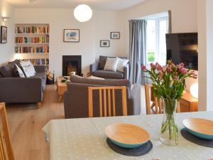 Una sala de estar con una mesa con platos y flores. en Lyndale, en Penzance