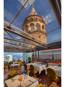 een restaurant met tafels en stoelen en een toren bij Anemon Galata Hotel in Istanbul