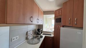 kuchnia z drewnianymi szafkami i zlewem w obiekcie Bajondillo Torremolinos Vistas al mar con piscina w mieście Torremolinos