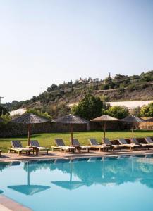 a group of chairs and umbrellas next to a swimming pool at Black & White Resort in Xylokastro