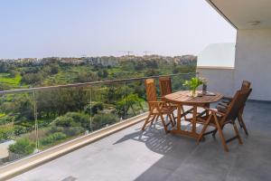 a balcony with a wooden table and chairs on a roof at Egħżien Suite A2 Access to Tranquil Shared Pool in Xagħra