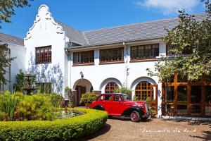 um velho carro vermelho estacionado em frente a um edifício branco em Kleinkaap Boutique Hotel em Centurion