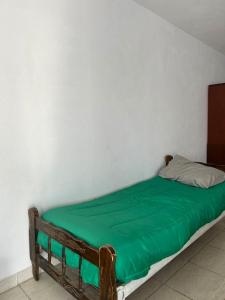 a bed in a room with a green blanket on it at Depto 3 in Río Cuarto