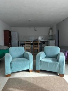 two blue chairs in a living room with a kitchen at Depto 3 in Río Cuarto