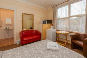 a room with a bed and a red chair and a window at Ricky Road Guest House - Budget in Watford