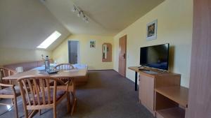 a living room with a dining table and a television at Haus Waldesruh in Petersdorf