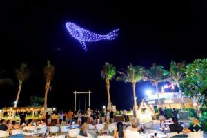 un groupe de personnes assises sur des chaises sur une plage la nuit dans l'établissement Apec-Mandala - Condotel - Ocean view-ADP TOUR, à Ấp Thiẹn Ái 69 autres photos