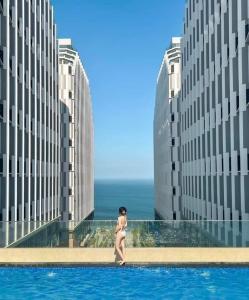 une femme marchant devant deux grands bâtiments dans l'établissement Apec-Mandala - Condotel - Ocean view-ADP TOUR, à Ấp Thiẹn Ái
