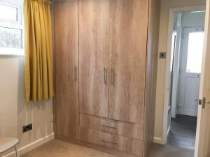a large wooden cabinet in a room with a window at Puffins in Port Isaac