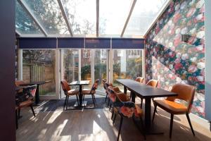 a restaurant with tables and chairs and a large window at Aadam Wilhelmina Hotel in Amsterdam
