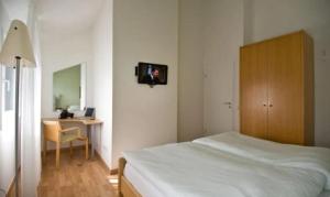 a bedroom with a bed and a desk with a tv on the wall at Haus Blinkfüer in Wangerooge