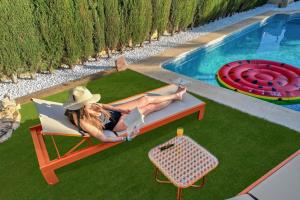 a woman sitting in a chair next to a swimming pool at Villa Elia, Cinema, Gym, KidsRoom, Pool & BBQ in La Eliana +65 photos