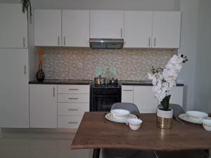 a kitchen with white cabinets and a wooden table with flowers at T0 Cabral Next Door in Sal Rei
