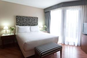a bedroom with a white bed and a large window at NH Córdoba Panorama in Córdoba