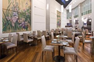 a dining room with tables and chairs and a painting at NH Córdoba Panorama in Córdoba