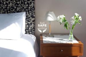 a bedroom with a bed and a table with a lamp and flowers at NH Córdoba Panorama in Córdoba