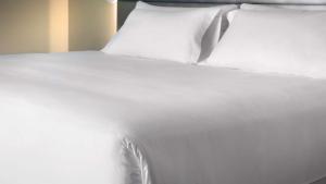 a white bed with white sheets and pillows at NH Córdoba Panorama in Córdoba