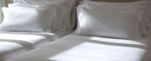 a bed with white sheets and pillows on it at NH Córdoba Panorama in Córdoba
