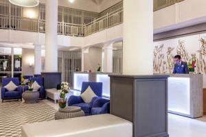 a lobby with blue chairs and a man in the background at Dunes d'Or Ocean Club in Agadir