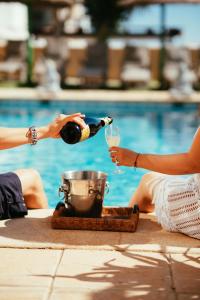 a person pouring a glass of wine next to a pool at Villa Dahi Almerimar 10 Guest, Prive Pool, Prive Bar, BBQ, Sea Views in Almerimar