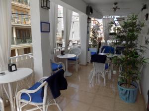 a restaurant with white tables and blue chairs at Hostal Villa Maruja in El Arenal