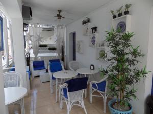 a restaurant with white tables and blue chairs at Hostal Villa Maruja in El Arenal
