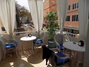 a balcony with white tables and chairs and a window at Hostal Villa Maruja in El Arenal