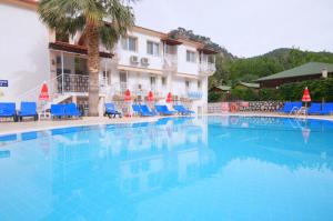 una gran piscina con sillas azules y un edificio en Karbel Beach Hotel en Oludeniz